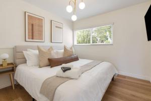a bedroom with a large white bed with a window at Trendy Getaway - Hot Tub - Putt Putt - Games in Long Beach