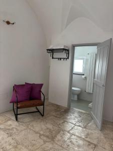 Un baño con una almohada morada sobre una silla y un inodoro. en Al numero 13, en Martina Franca