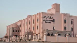 فندق النبراس AlNebras Hotel的一座大型粉红色建筑,上面有标志