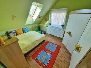 a small bedroom with a bed and a red rug at Balaton-parti Kertes Nyaraló in Keszthely