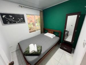 a small bedroom with a bed and a green wall at Alojamiento típico Calarca in Calarcá