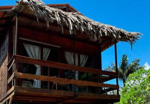 a building with a straw roof with a balcony at Pousada AldeiA Cotijuba in Belém