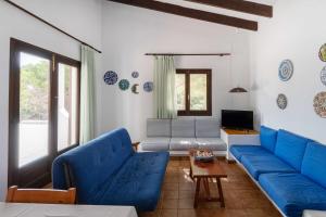 sala de estar con sofás azules y TV en Villa Menorquina con piscina en la playa, en Cala Morell