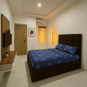 a bedroom with a bed with a blue comforter and a television at DPK Estate Cozy Room in Lekki