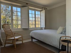 une chambre avec un lit, une chaise et des fenêtres dans l'établissement L'APPART enTHÈSE - Appartement pour une ou deux pers - Accessible à Tous - Meuble Tourisme 3 étoiles en BOURGOGNE, à Moloy