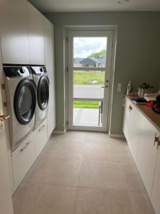 a kitchen with a washer and dryer next to a door at Moderne nybygget villa in Holstebro