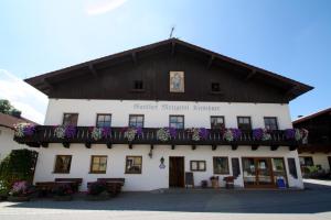 een groot wit gebouw met een balkon met paarse bloemen bij Ferienwohnungen Kirschner in Bad Birnbach