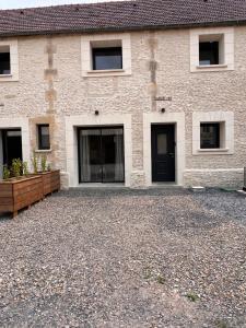 a building with black doors and a gravel driveway at Joli gîte familial in Airan