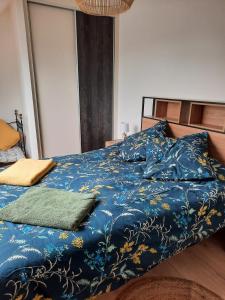 Bett mit blauer Bettdecke und 2 Kissen in der Unterkunft Maison 6 personnes in Saint-Méloir-des-Ondes