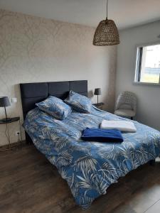 Bett mit blauer Bettdecke und Kissen darauf in der Unterkunft Maison 6 personnes in Saint-Méloir-des-Ondes