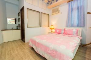 a bedroom with a bed with pink sheets and a lamp at 曉翠軒親子民宿 in Wujie