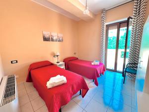 two beds in a room with red sheets at Appartamento La Via Roma in Torre deʼ Passeri