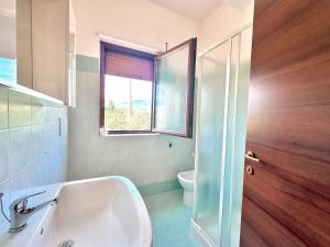 a bathroom with a sink and a toilet and a window at Appartamento La Via Roma in Torre deʼ Passeri +15 photos