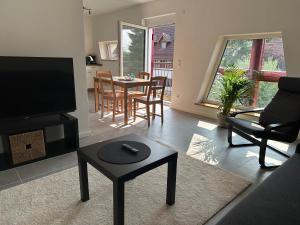 ein Wohnzimmer mit Fernseher und Tisch und Stühlen in der Unterkunft Ferienwohnung Seescheune 150m vom Ufer entfernt in Bodman-Ludwigshafen