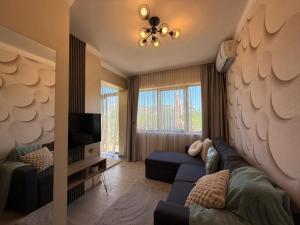 a living room with a blue couch and a tv at Sea Garden Escape - Byala in Byala