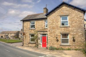 a brick house with a red door on a street at Cornlee in Aysgarth