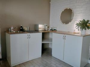 a kitchen with white cabinets and a sink and a mirror at Stay at Percy2 in Nelspruit