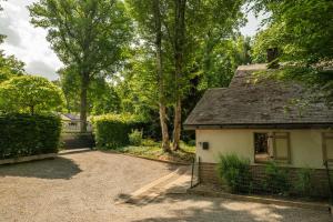a small white house with a fence and trees at Le Colibri spa jacuzzi in Durbuy