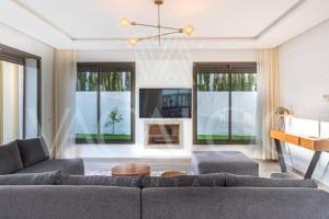 un soggiorno con un divano e una TV di Houd Taghazout - luxury villa - Pool - 6 or 7 Px a Taghazout Altre 17 foto