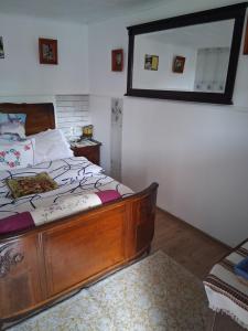 a bedroom with a wooden bed with a mirror on the wall at Casa Denis rustic in Turda