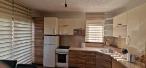 a kitchen with wooden cabinets and a white refrigerator at Panorama house in Sarajevo