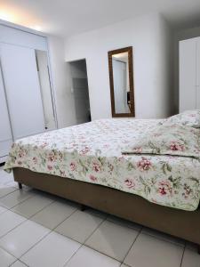 ein Schlafzimmer mit einem Bett mit geblümter Bettdecke in der Unterkunft Apartamento in Campina Grande