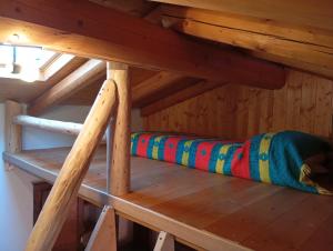 a loft bed in a wooden room with a colorful pillow at La Casetta in Breia