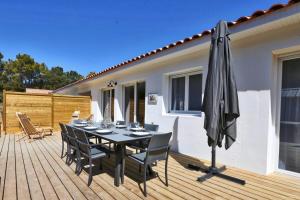 a table with chairs and an umbrella on a deck at Villa Tanzanie - Domaine Le Sherwood in Notre-Dame-de-Monts