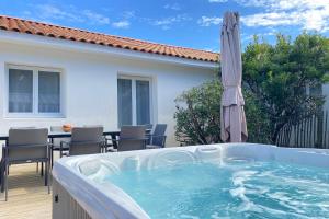 a hot tub with an umbrella on a patio at Villa Tanzanie - Domaine Le Sherwood in Notre-Dame-de-Monts