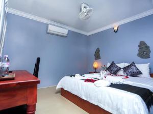 a bedroom with a bed with blue walls and a desk at Cheng Lay Guesthouse in Siem Reap