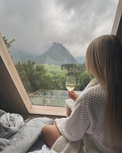 a woman holding a glass of wine looking out a window at Cabana do Céu - Soldados Sebold in Alfredo Wagner