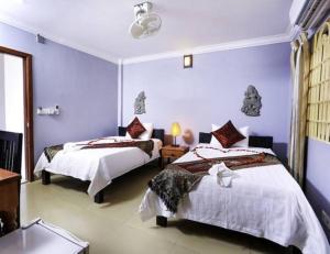 two beds in a room with blue walls at Cheng Lay Guesthouse in Siem Reap
