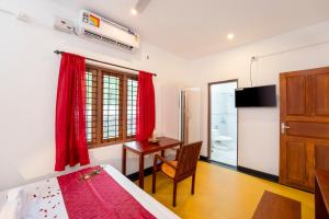 - une chambre avec un lit, un bureau et des rideaux rouges dans l'établissement Ananda Marari Heritage Villa, à Alappuzha