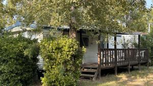a small white house with a porch and a wooden deck at AdriaCamp Mobile Homes Rosapineta in Rosapineta