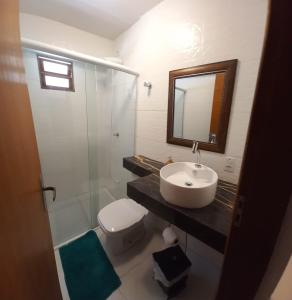 Un baño con lavabo, inodoro y espejo. en 02 Lindo apartamento da pedra com churrasqueira, en São Sebastião