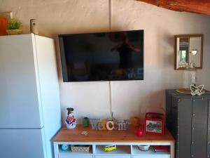 a flat screen tv hanging on a wall next to a refrigerator at Cercado de arriba in Cortelazor