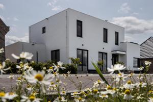 a white house with black windows and white flowers at The White House Apartment in Tholen