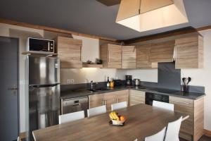 a kitchen with wooden cabinets and a table with bananas on it at CGH Résidences & Spas les Chalets du Soleil Contemporain in Les Menuires