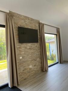 a flat screen tv on a brick wall with windows at Mountain House Transalpina in Novaci +11 photos