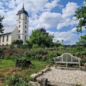 a white bench in front of a building with a clock tower at Ferienhaus Rumpelt in Kurort Gohrisch