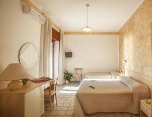 een slaapkamer met een bed, een bureau en een spiegel bij Hotel Royal in Villammare +39 foto's