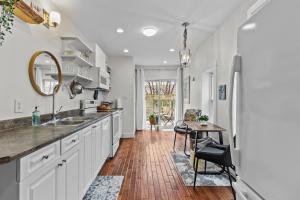 a kitchen with white cabinets and a sink and a table at Stay on Bond 2BR Queen Deck Vws in St. John's
