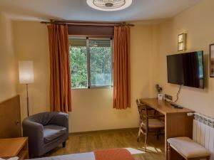 a room with a desk and a tv and a chair at Hotel Don Pepe Lago de Sanabria in Ribadelago