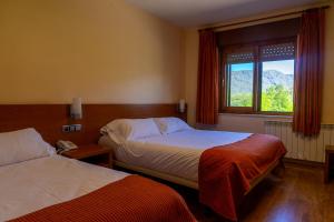 a hotel room with two beds and a window at Hotel Don Pepe Lago de Sanabria in Ribadelago