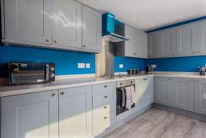 a kitchen with white cabinets and blue walls at Room 2, 23 Deganwy Avenue in Llandudno