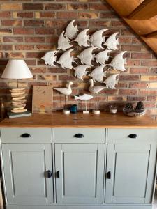 a white cabinet with a lamp on a brick wall at Maison calme Quend-Plage Petite Californie in Quend-Plage