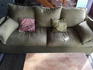 a leather couch with two pillows and a coffee table at Maison calme Quend-Plage Petite Californie in Quend-Plage