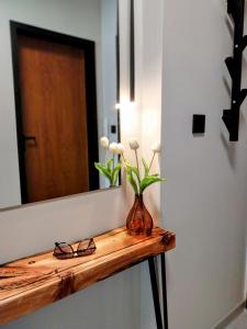 una mesa con espejo y un jarrón con flores en Ika Apartment Central, en Burgas
