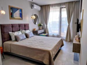 Un dormitorio con una cama grande con una ventana grande. en Ika Apartment Central, en Burgas