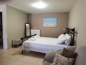 a bedroom with a white bed and a couch at Anna's Cozy Home in Argostoli